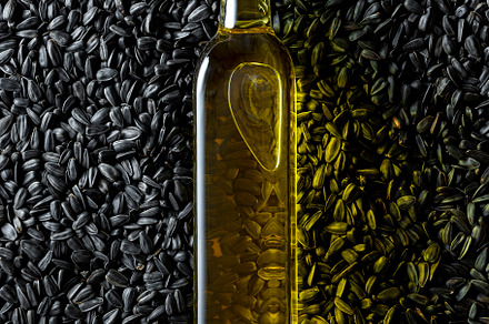 Oil bottle on a pile of black sunflower seeds, above view., a Food & Drink Photo by YesPhotographers