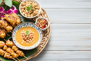 Satay skewers and shrimp with rice, sauces, and orchids arranged, a Photo by Dvoevnore photos