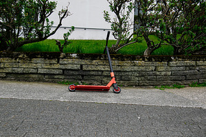 Red scooter resting near a stone wall in Reykjavik, Iceland, a Photo by AS photostudio