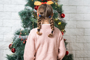 Young girl looking at decorated Christmas tree from behind, a Holiday Photo by etorres69