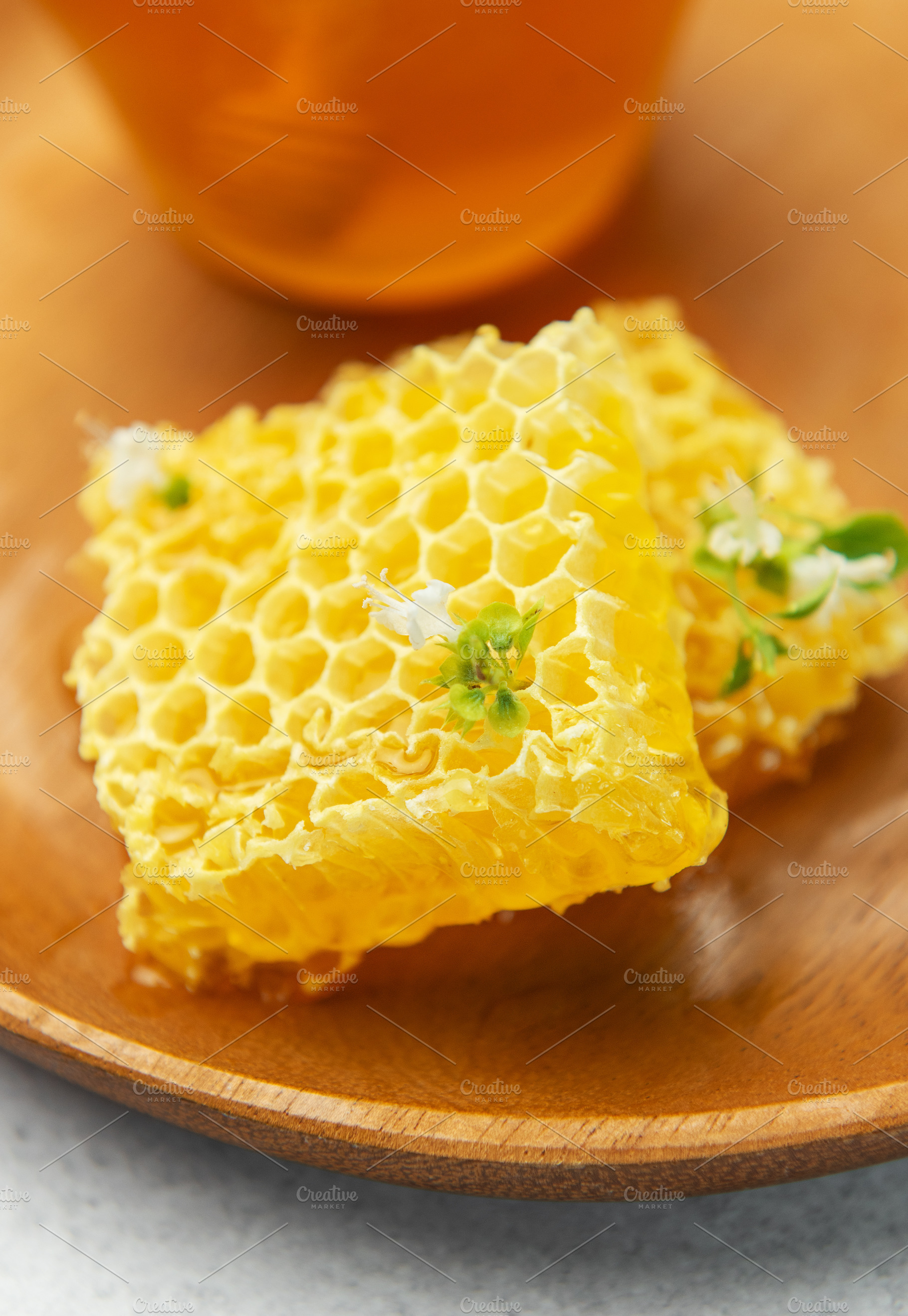 Fresh honeycomb with flower on wooden plate and honey in glass j, a Food & Drink Photo by Olena Rudo