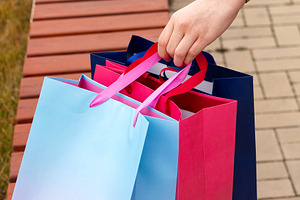 Shopper's hand grasping vibrant bags, a Background Photo by Elena Vagengeim