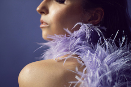 portrait woman in an evening purple dress with feathers stands in the backgroun, a Person Photo by SaulichPhoto