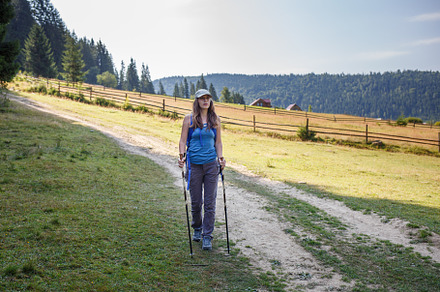 Young woman hiking with poles through a valley in mountains, a Sports & Recreation Photo by serkum