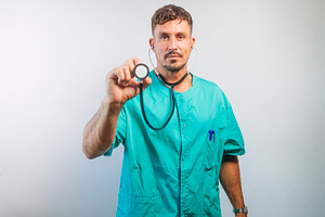 Serious Doctor Holding Stethoscope Forward, a Person Photo by karrastock