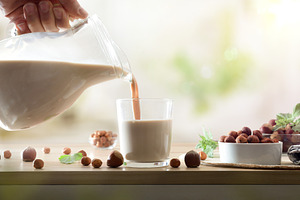 Filling glass with hazelnut drink on wooden kitchen bench, a Food & Drink Photo by Davizro's Market