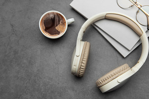 Wireless headphones, hot coffee and notebooks resting on gray ta, a Business Photo by Olena Rudo