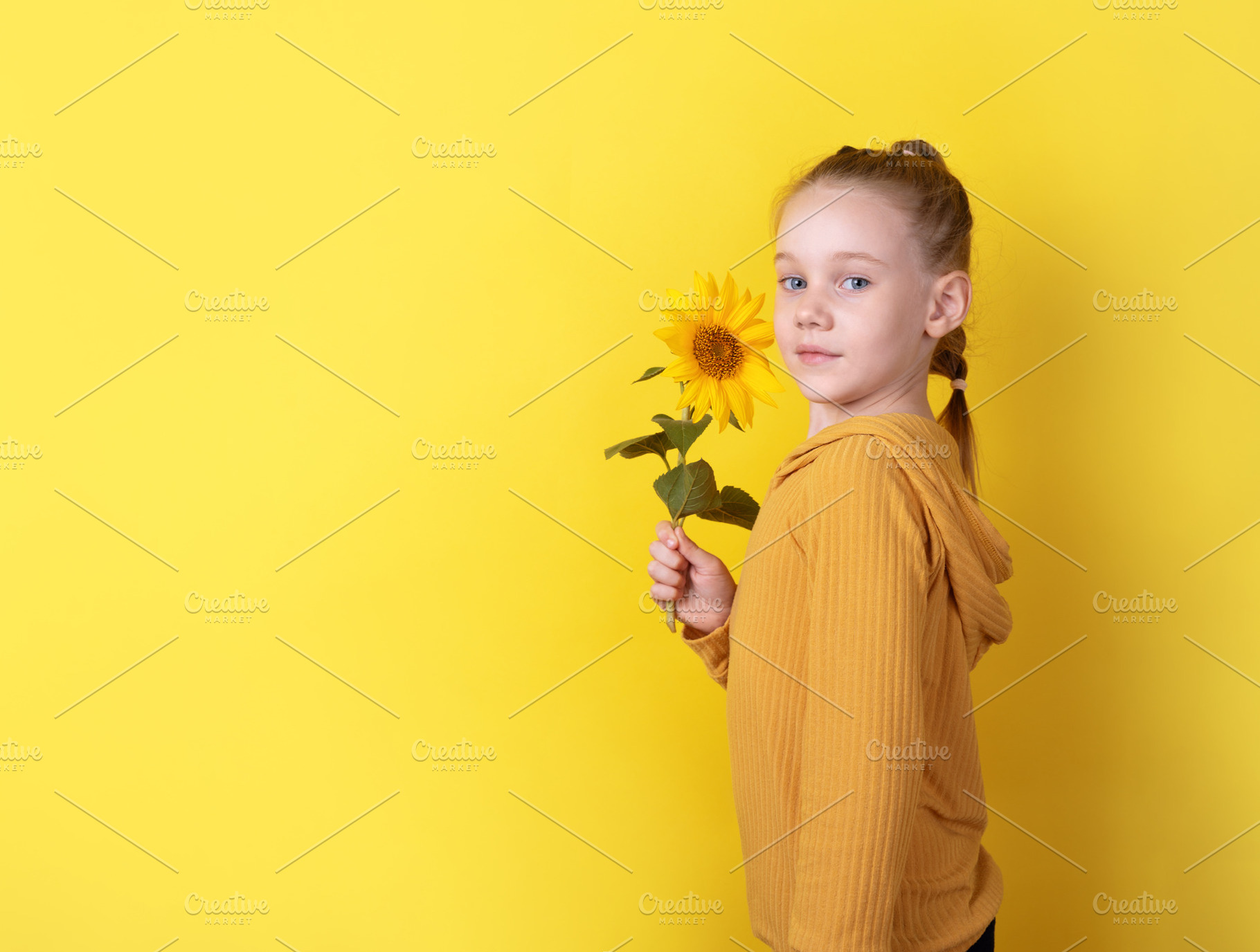 Smiling young girl holding a sunflower, standing against a vibra, a Person Photo by Ales Munt