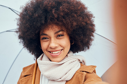 Woman, selfie closeup and umbrella in rain, water or drizzle in portrait, happiness and smile. Black woman, hair or afro beauty with parasol for protection from elements, climate or outdoor in city, a Photo by Peopleimages.com