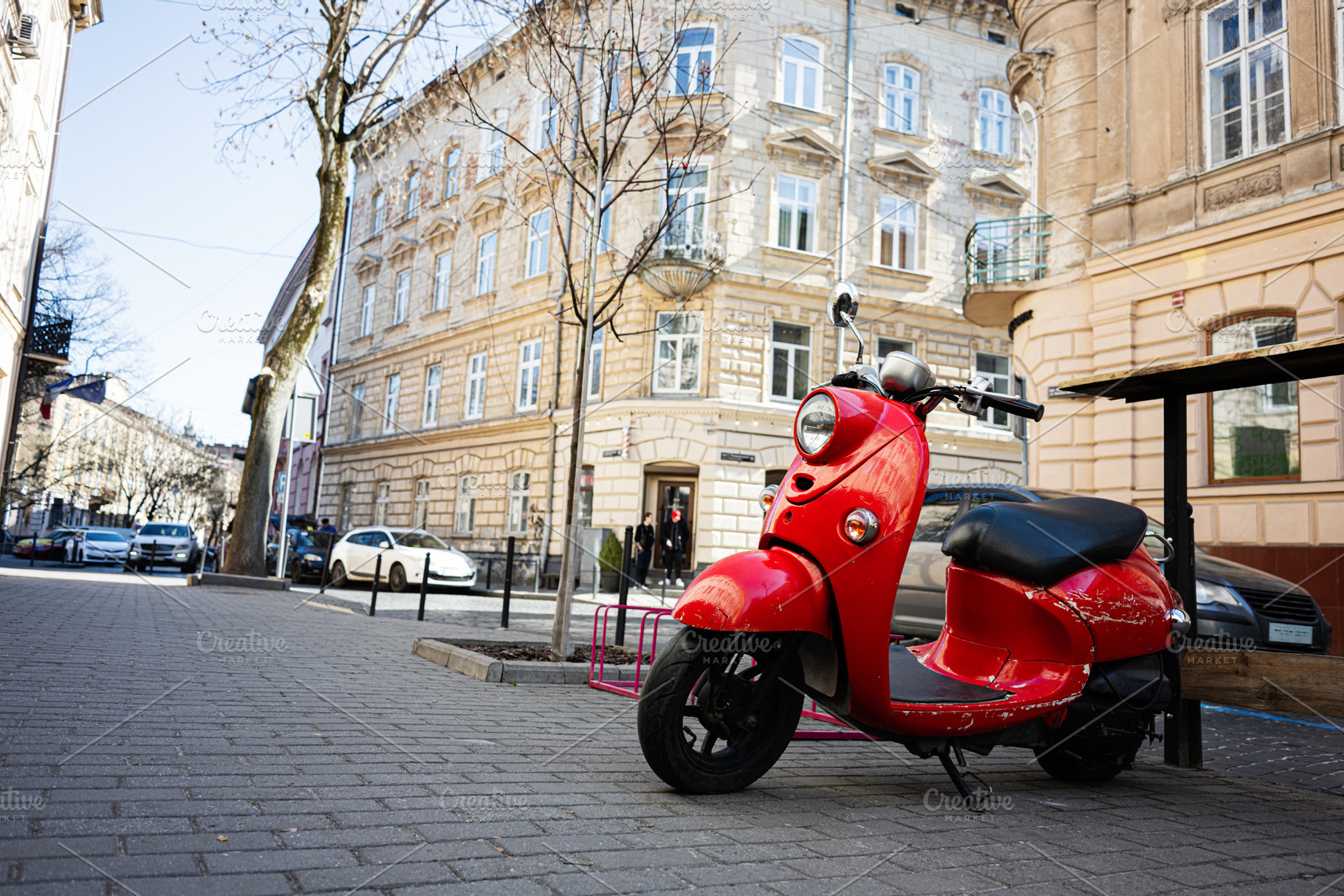 Red scooter parked on a street with classic European architecture, a Photo by AS photostudio