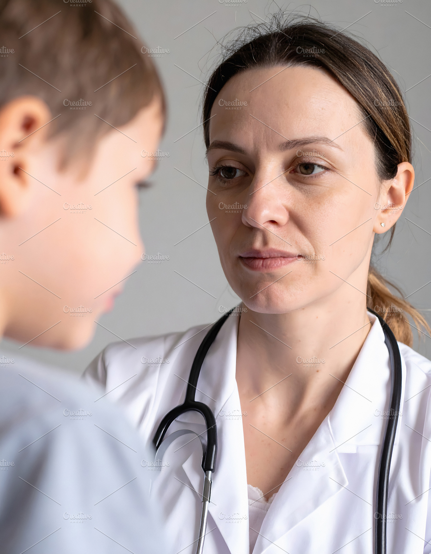 Woman doctor listening carefully to child during consultation, a Person Photo by GoodGoods