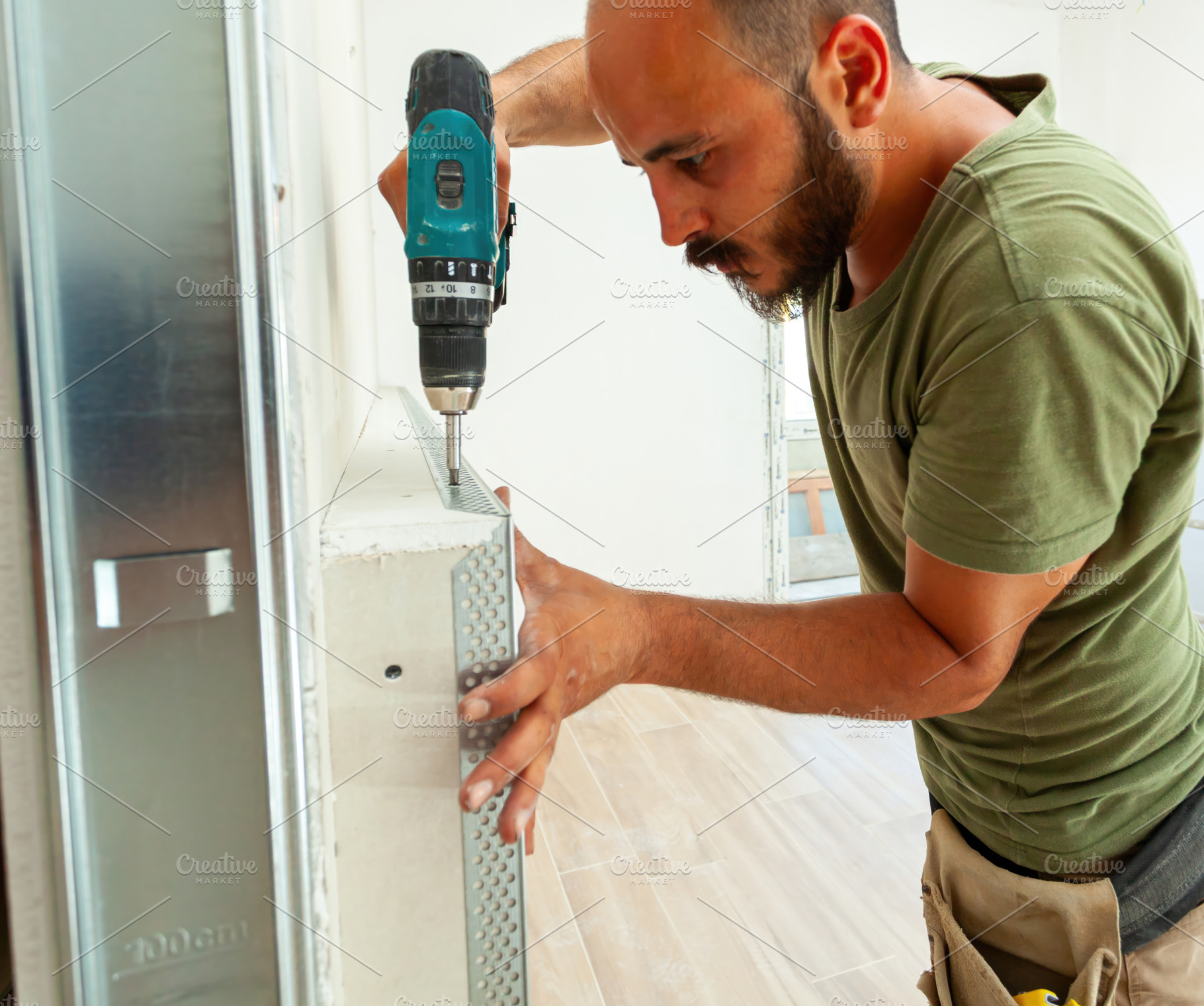 Construction worker installing metal corner bead on drywall with cordless screw, an Industrial Photo by Antonio Gravante Market