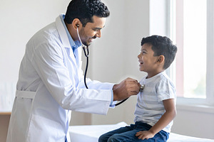 Pediatrician examining a cheerful child with a stethoscope in a, a Health & Medical Photo by DanFLCreativo
