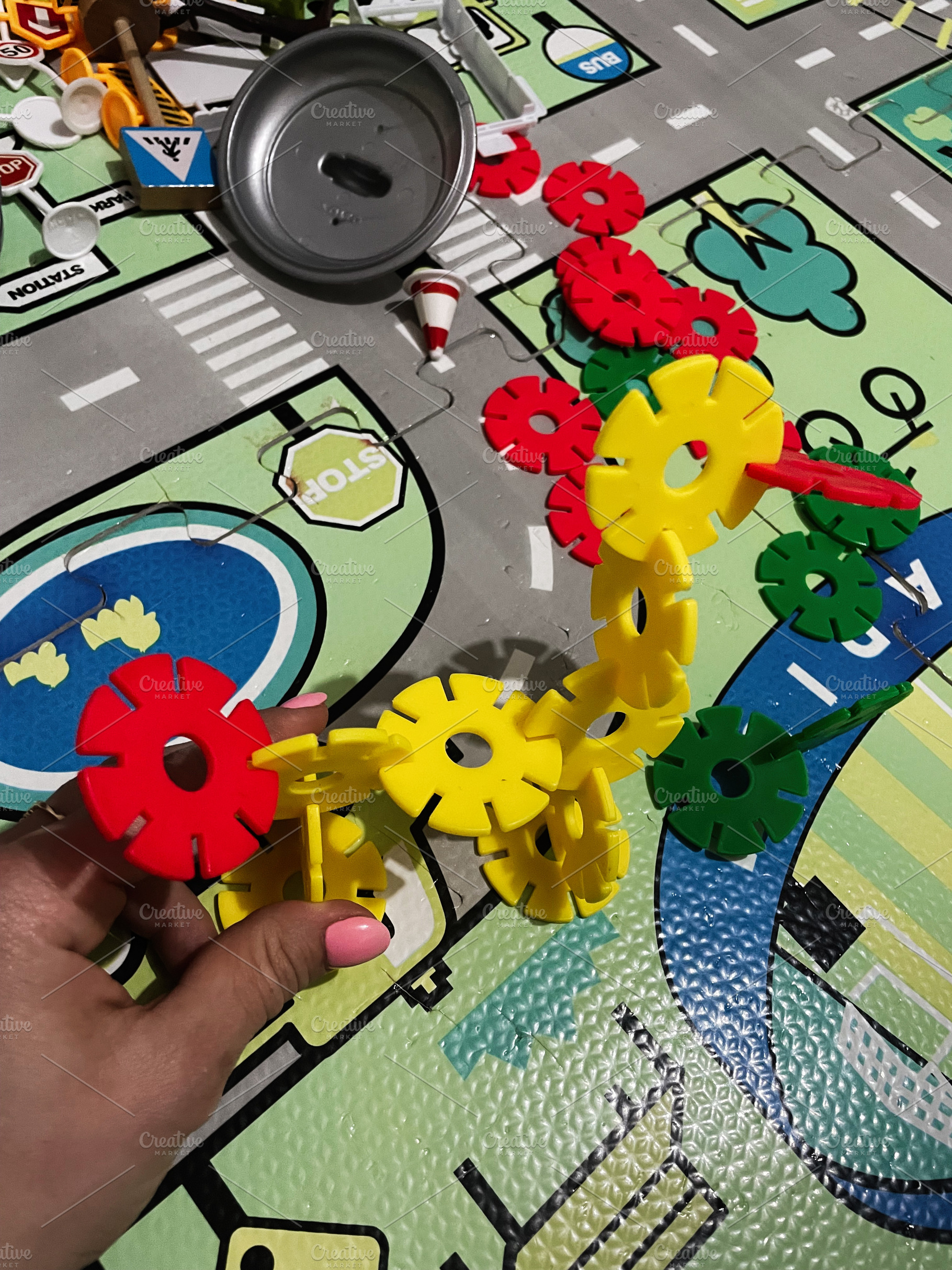 Colorful construction toy pieces on play mat decorated with cityscape streets, a Photo by AS photostudio