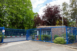 Secure gated entrance with blue metal fence and guardhouse at a