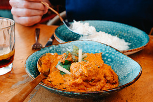 a man seated a table with tikka masala and rice, a Photo by Nito