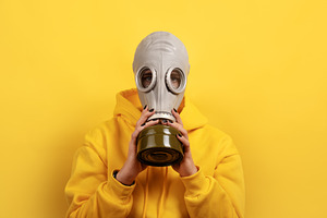 Individual wearing a gas mask and yellow hoodie standing against, a Person Photo by Ales Munt