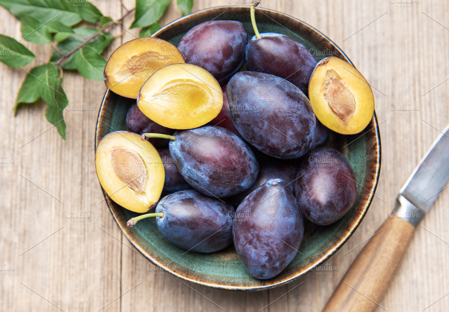 Fresh ripe plums in bowl on wood surface, a Food & Drink Photo by Olena Rudo