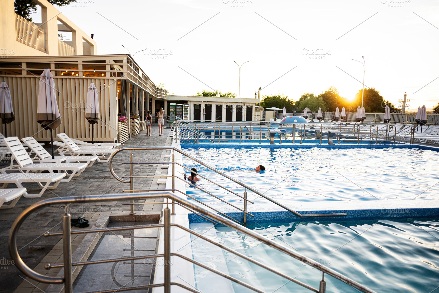 Outdoor swimming pool with lounge chairs and umbrellas under a serene sunset, a Photo by AS photostudio
