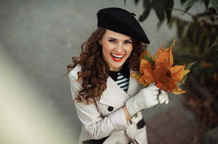 happy elegant woman in beige trench coat and black beret, a Person Photo by Alliance Images