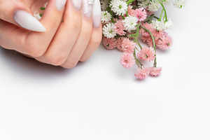 Woman's hands holding flowers with stiletto nail art manicure, a Photo by Olena Rudo