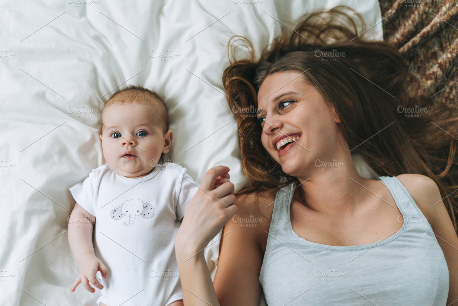 Young mother with baby girl on bed, a Person Photo by Galina_Zhigalova