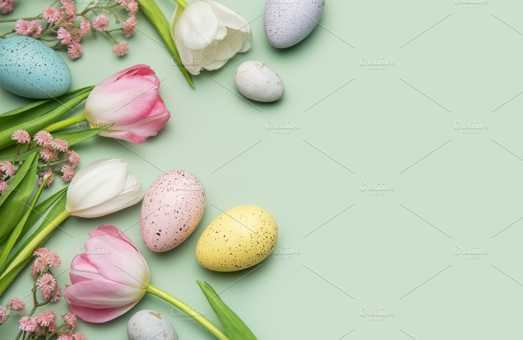 Easter eggs and tulips creating a border on pastel green backgro, a Photo by Olena Rudo