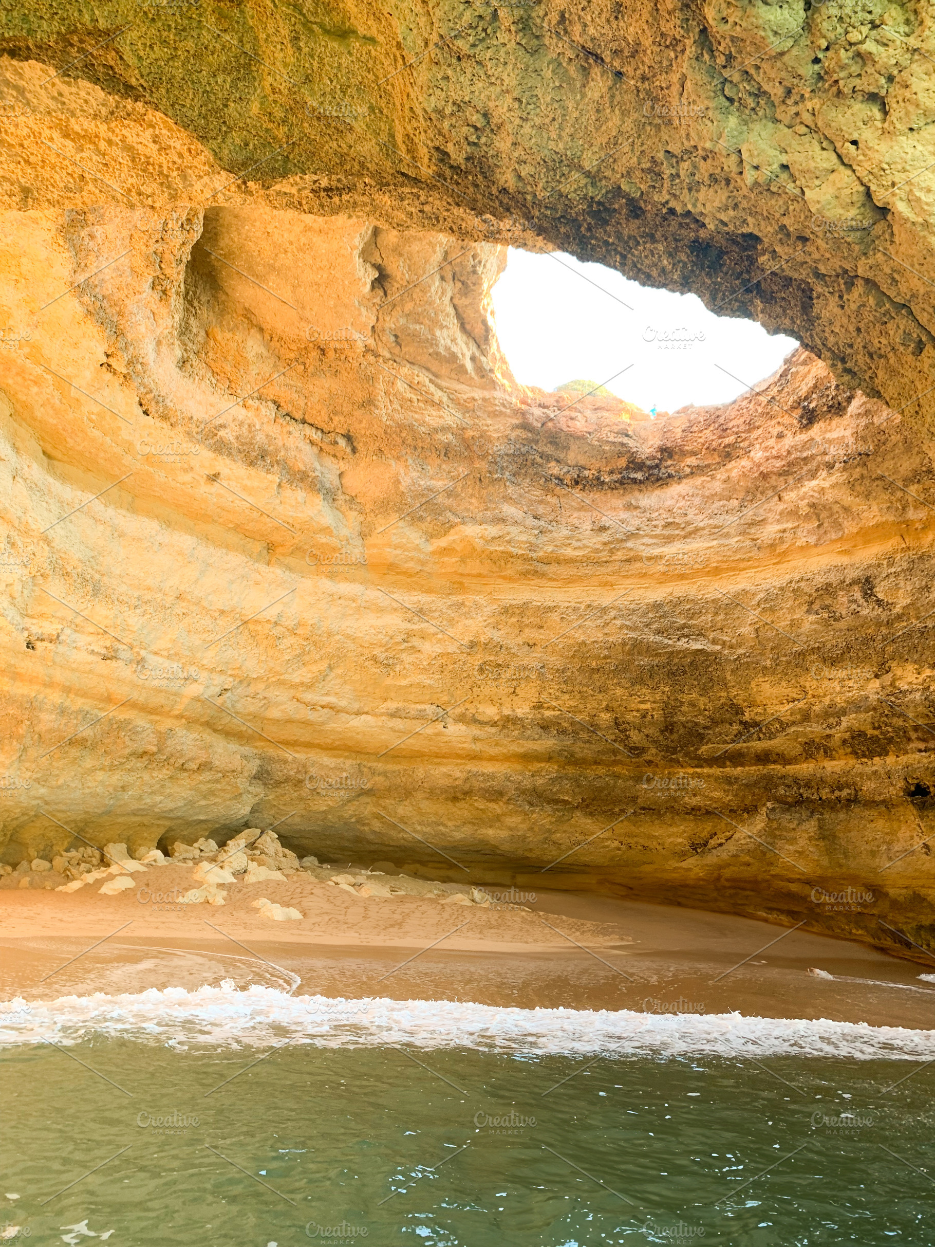Coastal cave with golden cliffs and turquoise water. Sunlight st, a Holiday Photo by sebastianaraw
