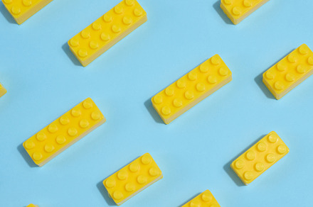 Scattered yellow plastic toy building bricks on a blue backgroun, a Background Photo by ndanko