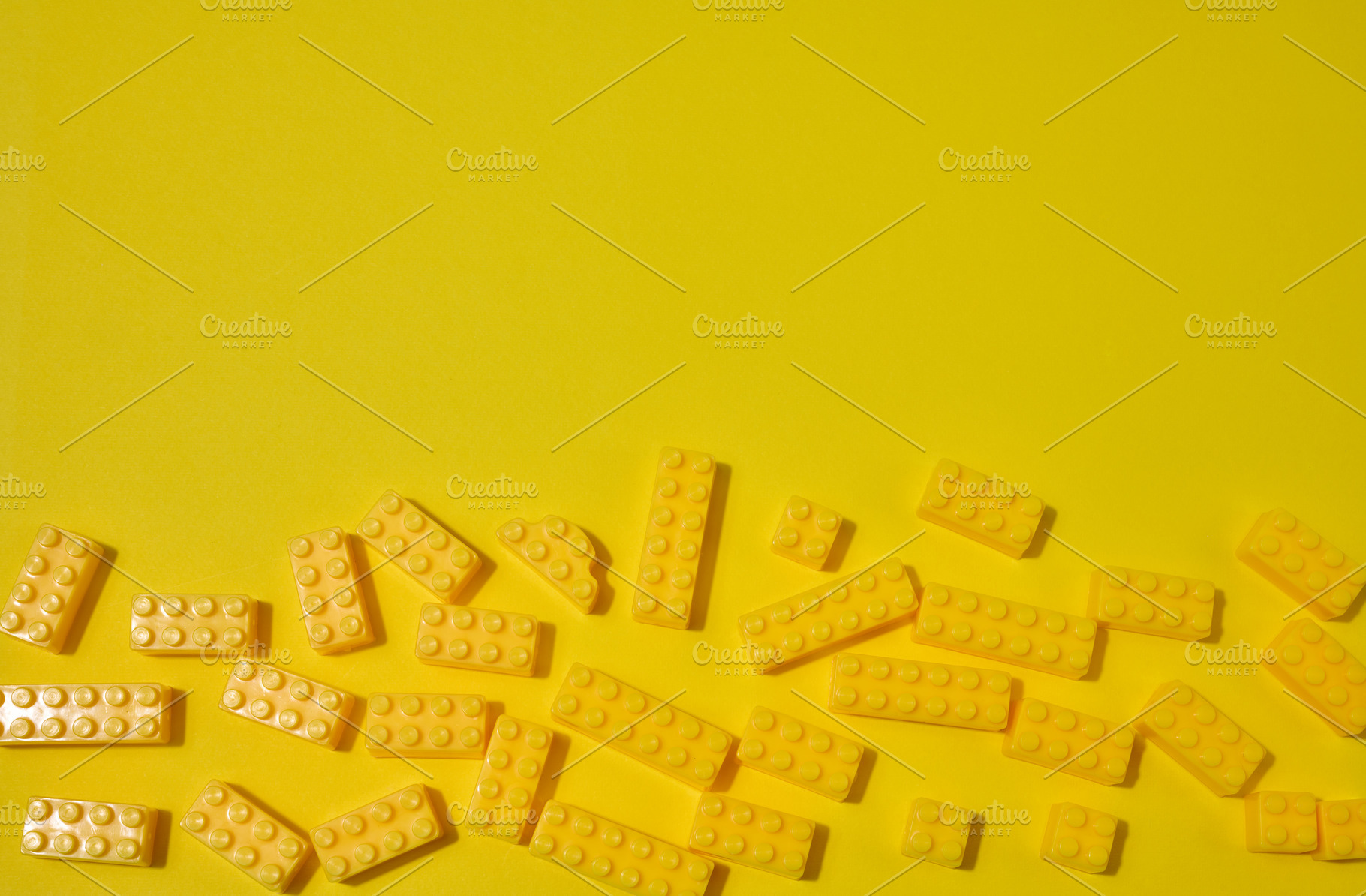 Scattered yellow plastic toy building bricks on a solid yellow b, a School & Education Photo by ndanko