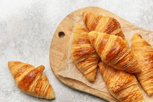 Freshly baked croissants on wooden board, a Food & Drink Photo by Olena Rudo