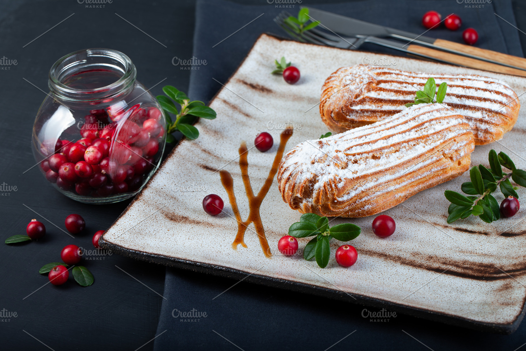 Cream eclairs choux pastries served with fresh cranberries on a, a Food & Drink Photo by eleana