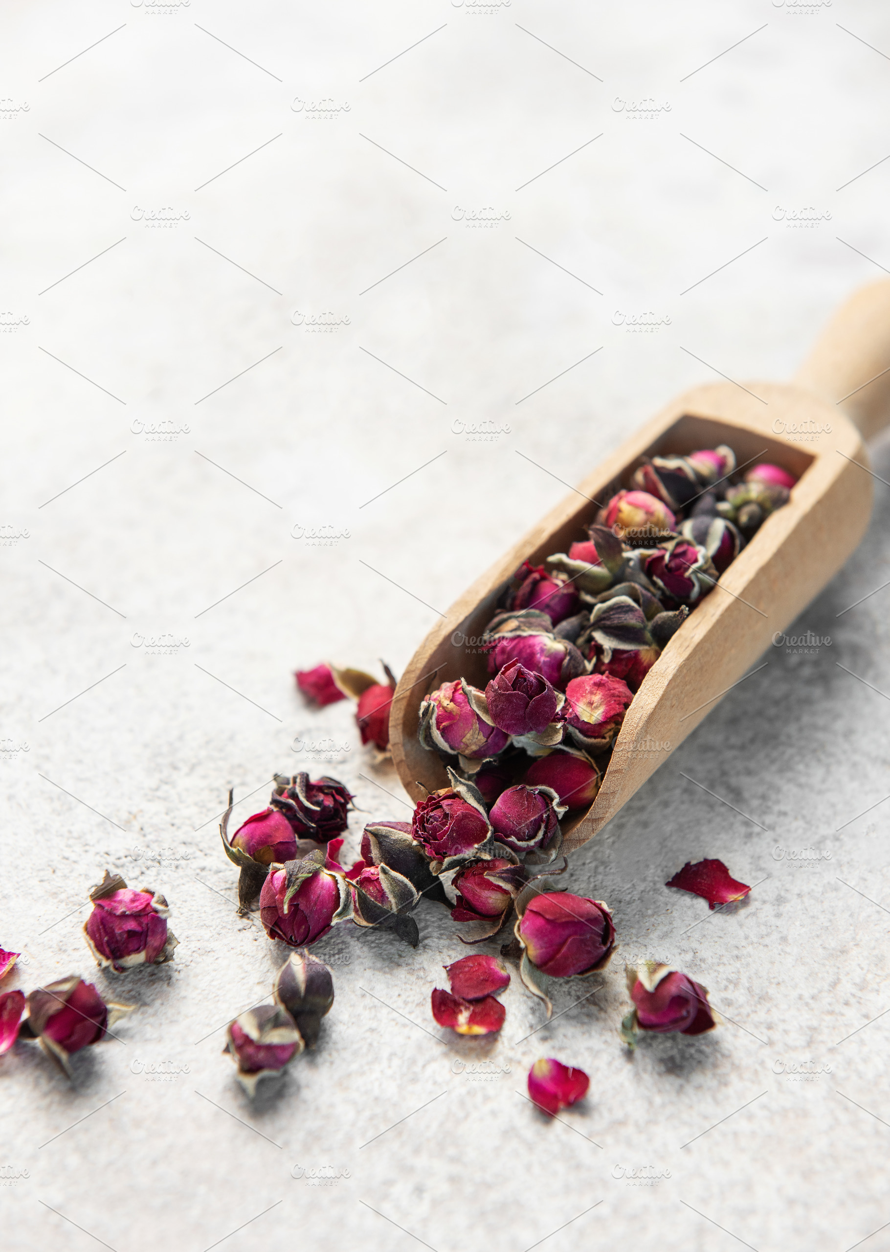 Dried rose buds spilling from wooden scoop, a Food & Drink Photo by Olena Rudo