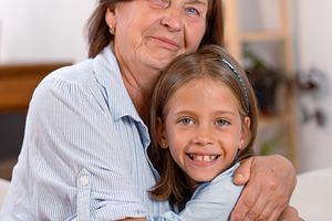 Contented grandmother and granddaughter embracing each other at home, a Photo by andreonegin market