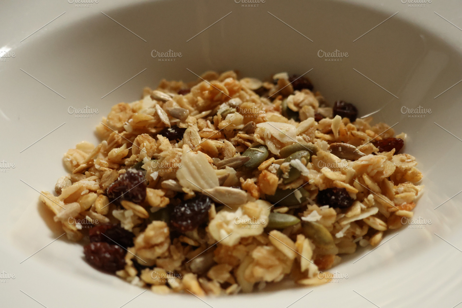 Granola mix filling white bowl, representing healthy breakfast o, a Photo by Studio ANNA