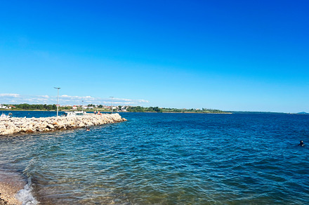 Serene coastal scene with clear blue water and rocky shoreline, a Photo by AS photostudio