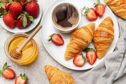 Delicious breakfast with coffee, croissants, strawberries, and h