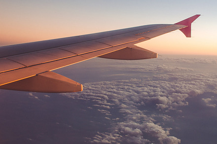 Airplane wing with sunrise featuring above, aircraft, and airplane