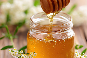 Close-up of a glass jar filled with honey and a wooden dipper on a rustic woode, a Photo by AlyaAnd