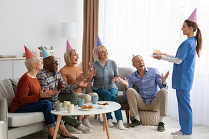 Excited elderly people having birthday party at nursing home, panorama, a Photo by Prostock-Studio