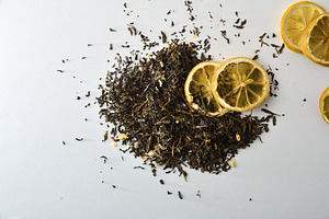Detail of tea leaves on white table with lemon slices, a Food & Drink Photo by Davizro's Market
