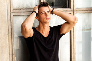 Young man posing with hands in hair by window, a Person Photo by RF Images