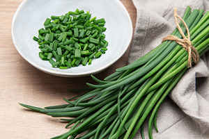 Freshly cut chives in a bowl resting on wooden table, a Food & Drink Photo by Olena Rudo