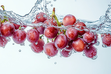 Bunch of grapes falling into water on white background, a Food & Drink Photo by AlyaAnd