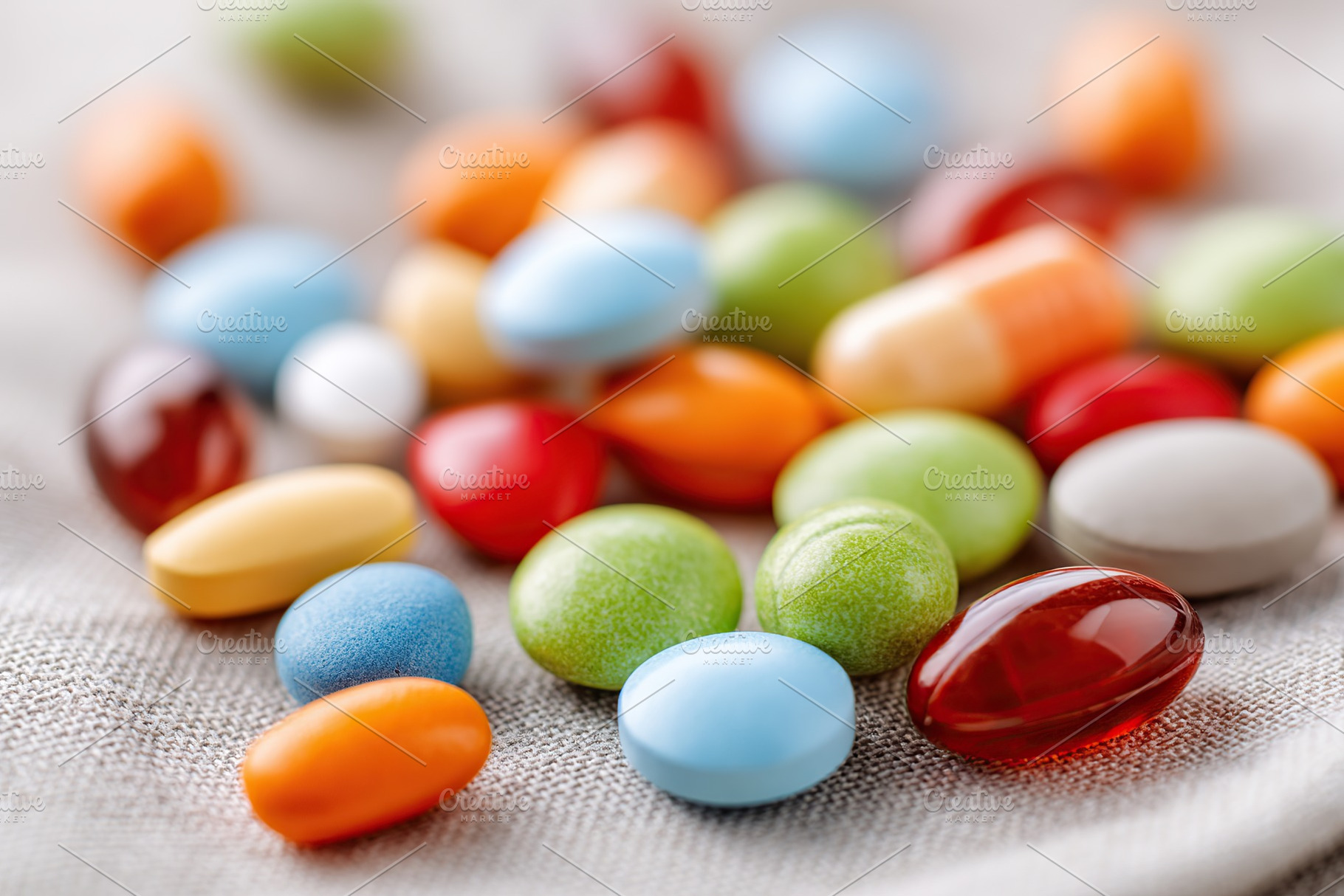 Colorful assortment of candies and vitamins displayed on a textured fabric surf, a Health & Medical Photo by AlyaAnd