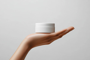 White cream jar in a hand skincare p, a Background Photo by Pixeness Studio