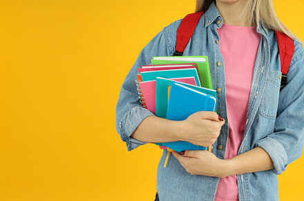 Student girl with notebooks on yellow background, a School & Education Photo by AtlasStudio PRO