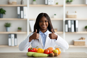 Young african american female nutritionist recommending eating fruits and veget, a Person Photo by Prostock-Studio