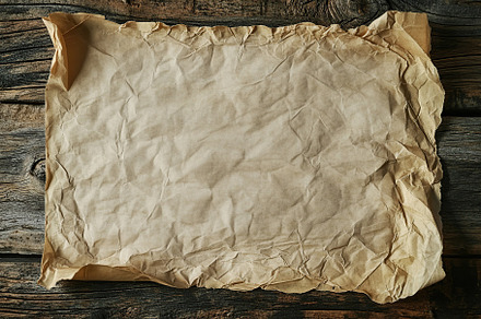 Wrinkled sheet of paper on wooden table, a Background Photo by AlyaAnd