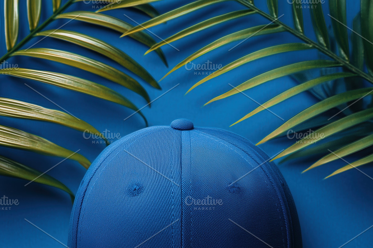 A blue baseball cap mockup placed on a vibrant blue background surrounded by gr, a Hat Mockup by Textures & Backgrounds